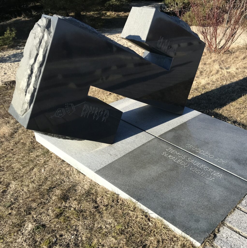 Die große Steinskulptur im Nord-Westen hat die Form eines liegenden, kantigen Buchstabens S. In der Bodenplatte die litauische Inschrift "22. Dezember, Wintersonnenwende, Weihnachtsnacht"