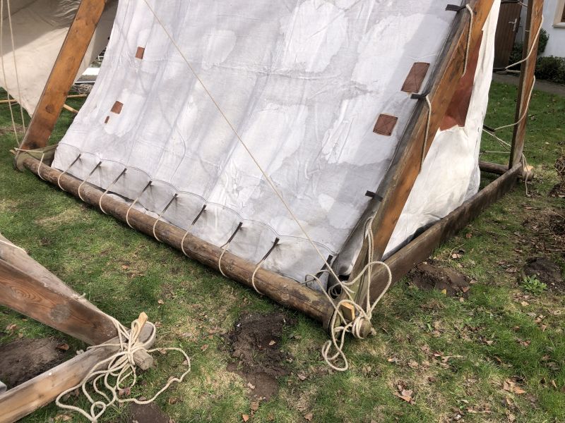 Hier wird die Abspannung der Zeltplane unten an der hölzernen Längsstange des "Eichenzeltes" gezeigt.